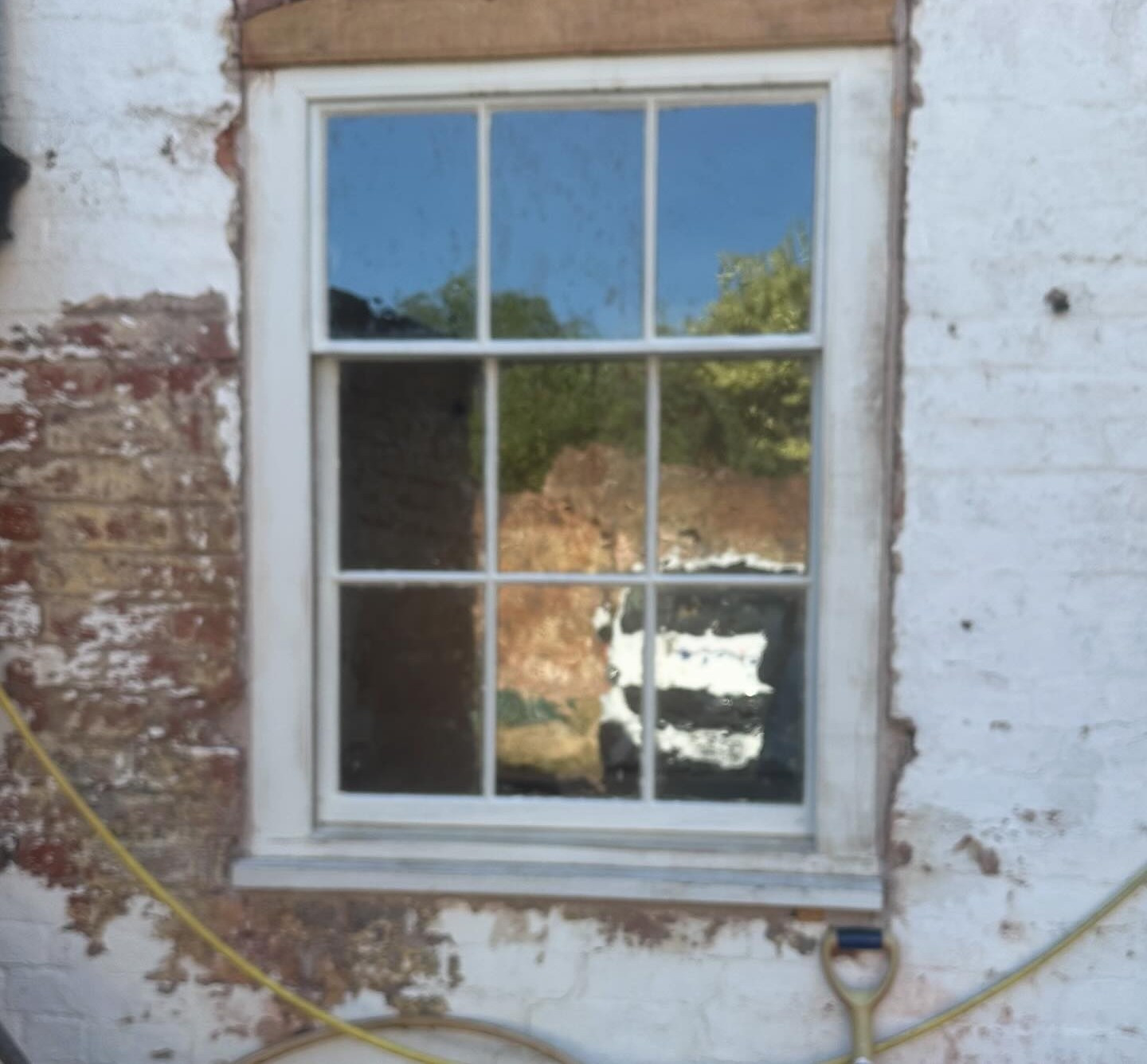 Sash window glazed with Wibble Restoration Glass in an old limewashed brick wall
