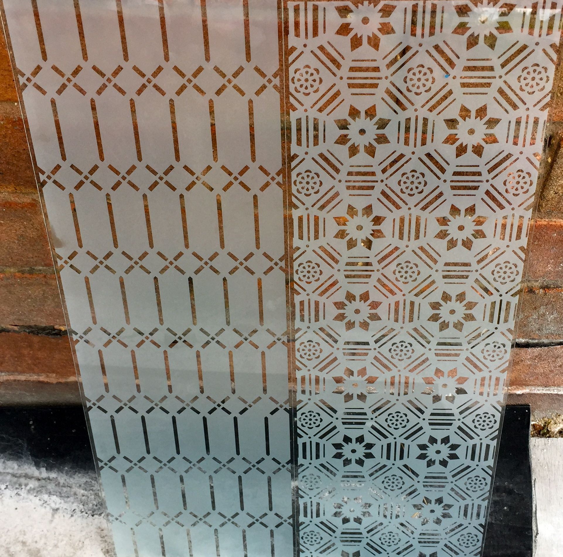 Two etched geometric glass panels side by side
