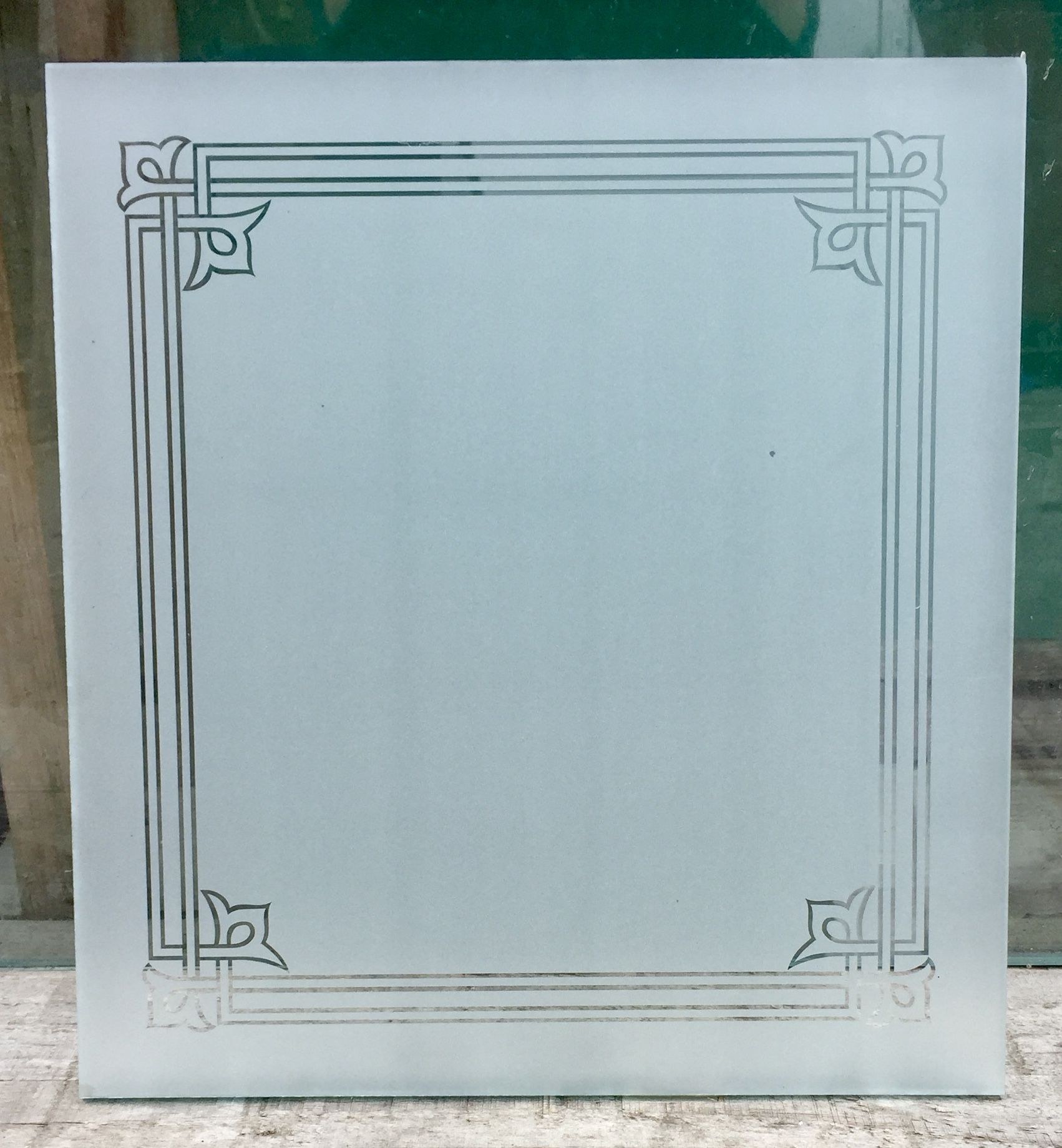 Frosted panel with an etched decorative border and corner motifs
