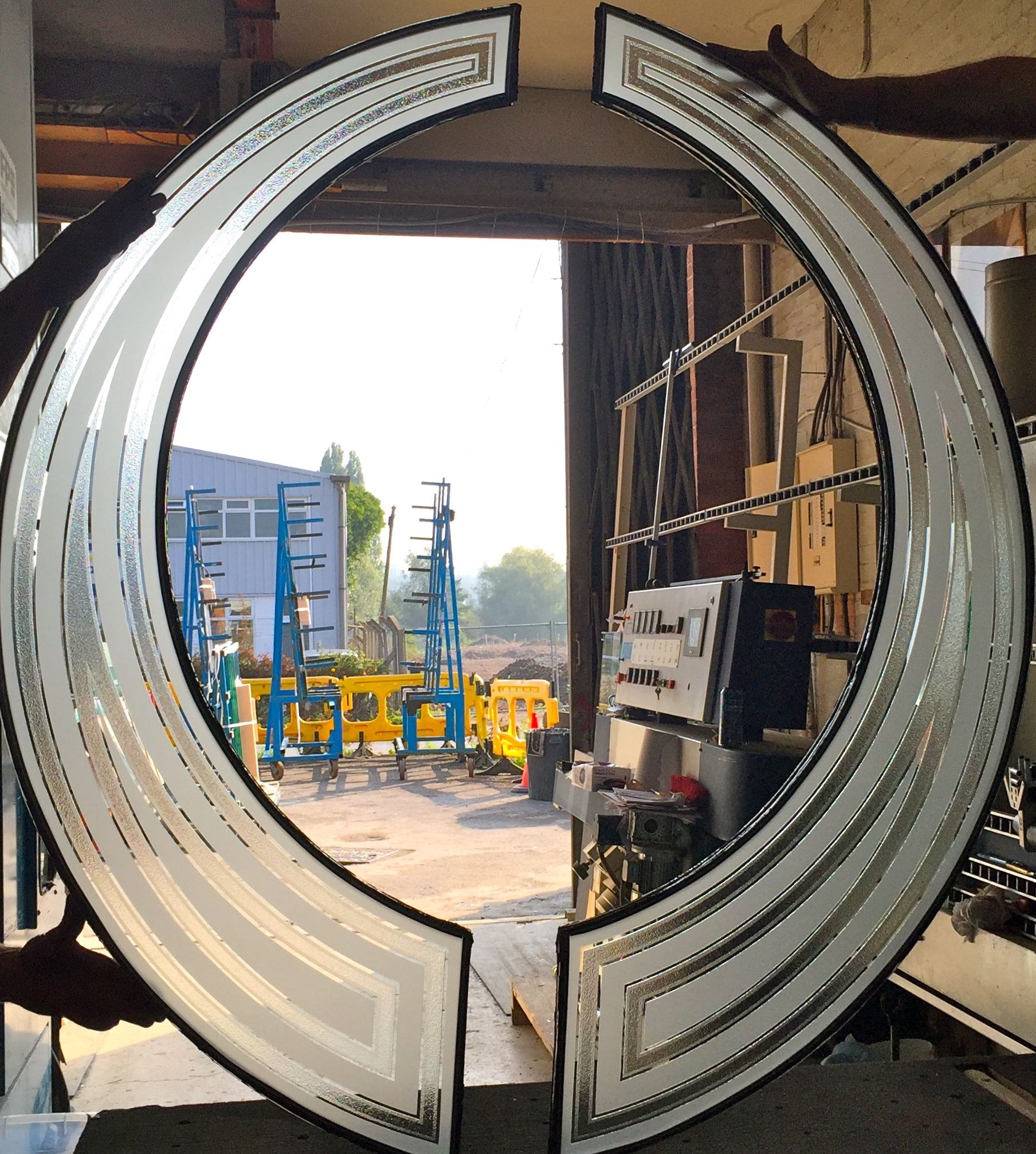 Curved etched glass ring standing in the workshop doorway