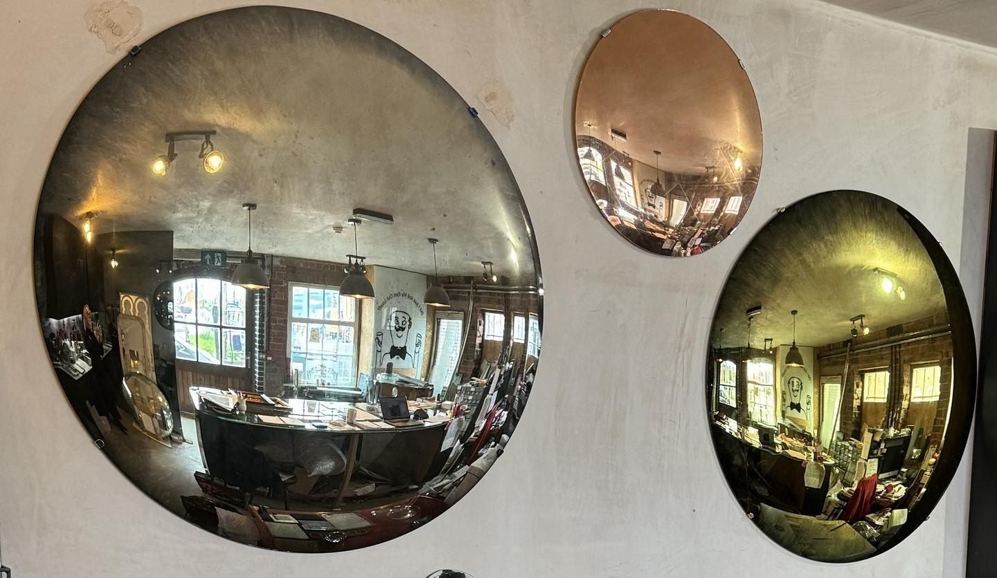 Three hand-antiqued convex mirrors in silver, copper leaf and gold on a wall